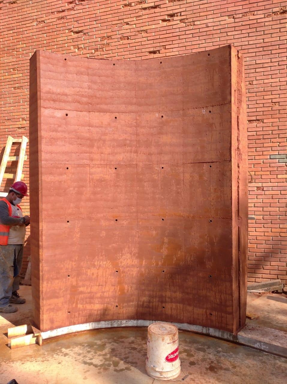 Tramo de muro curvo recién desencofrado, con las capas de tierra apisonada a la vista