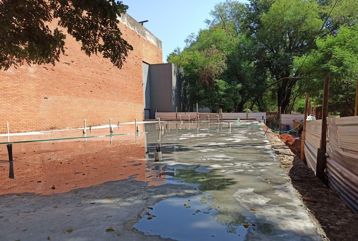 Platea de hormigón terminada junto al auditorio, en curado con agua
