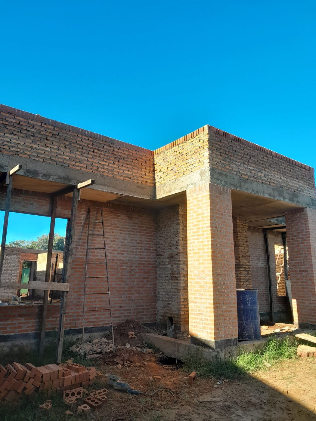 Frente de un edificio de ladrillo visto en construcción, con pórtico de acceso