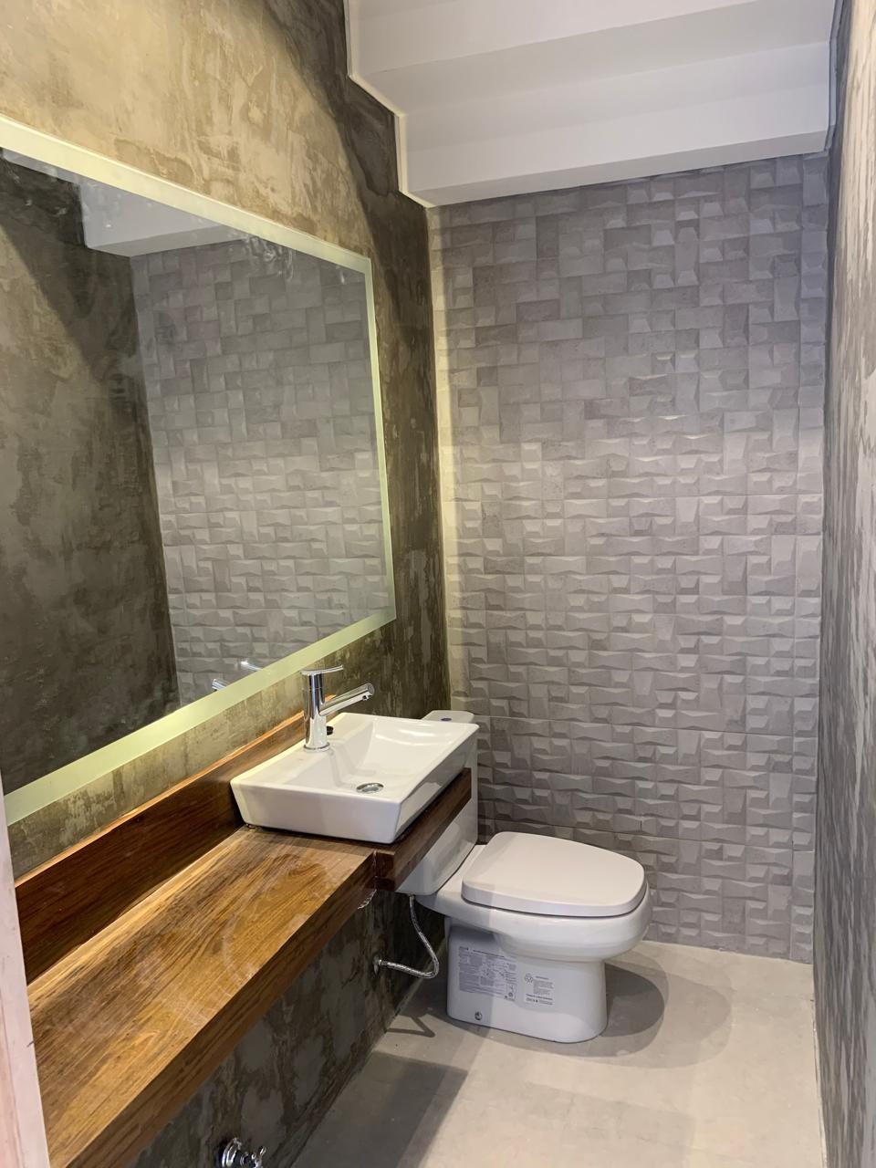 Baño con revestimiento en relieve, mesada de madera y espejo con luz