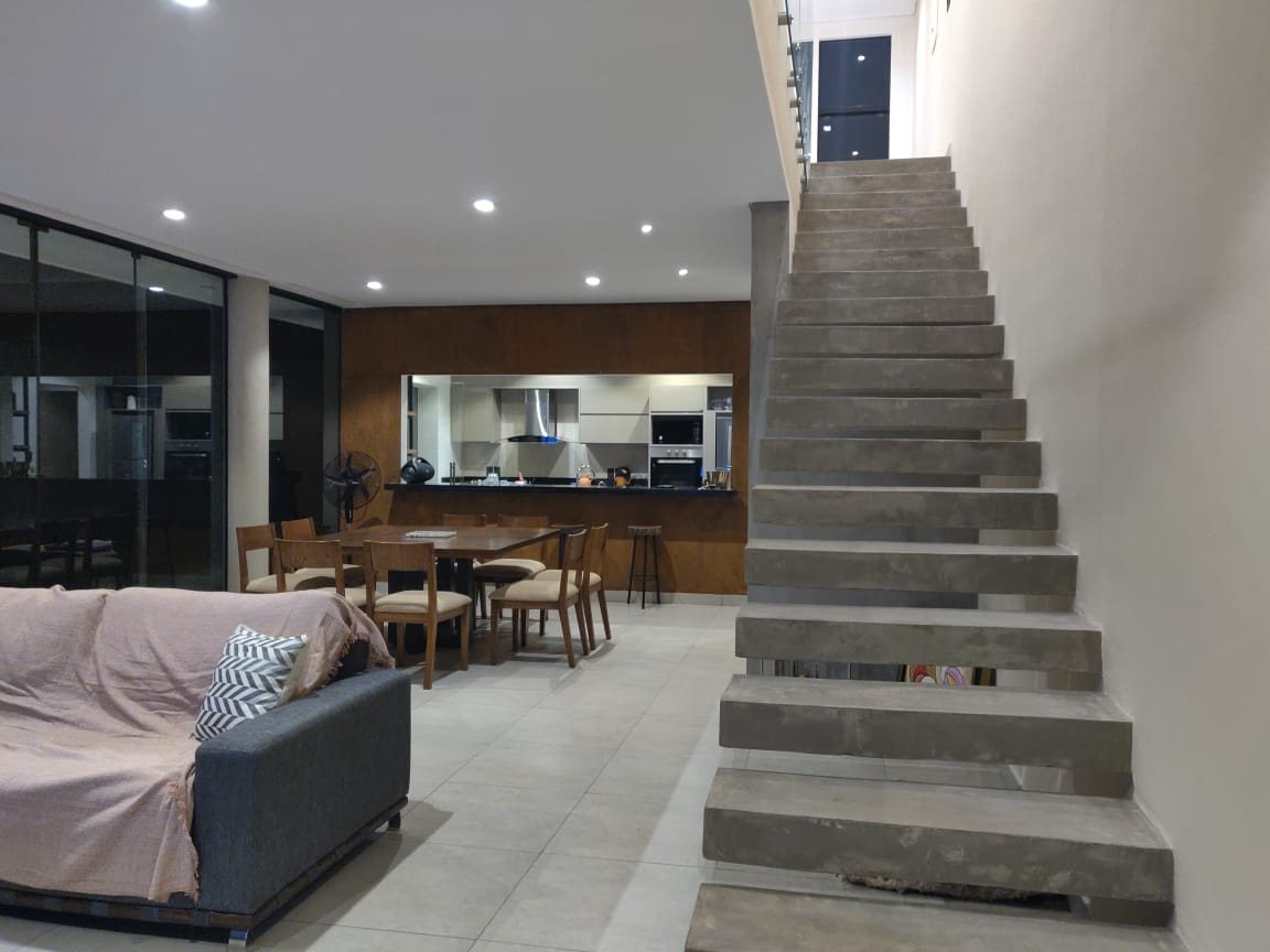 Estar comedor con escalera de hormigón visto y cocina integrada